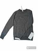 Full view of grey Lululemon scuba crew neck sweater with tags showing two front pockets and ribbed sleeve cuffs.