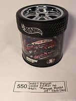 Front angled view showing red metallic Mongoose Rocket Oil dragster within tire-shaped display case with Hot Wheels branding.