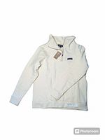 Front view of cream-colored Patagonia Woolie fleece pullover sweater laid flat, showing full garment and half-zip collar.