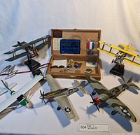 Overview photo showing all five model planes and the open wooden cigar box with military pins inside.