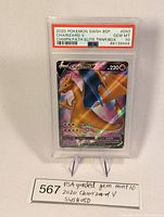 Front of the graded Charizard V card with PSA Gem Mint 10 label, displayed on stand with lot number card