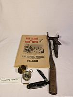 Overview of all items in the lot including the book, compass, rigging cutter, and rigging knife.