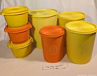 Full lot of vintage orange and yellow Tupperware nesting containers with lids, showing size variation and design.