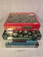 Three sealed puzzle boxes stacked: top is I Spy 500 piece marble puzzle, middle is double-sided Impossipuzzle, bottom is 1000 piece Photo Mosaic puzzle by Robert Silvers.