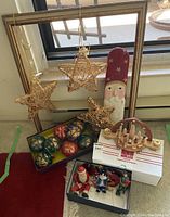 Overall lot arranged by window including stars, boxed ornaments, wooden nativity candle holder and figurines.