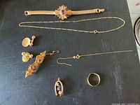 All pieces laid out: bracelet, two chains, cufflinks, pins, ring