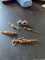 Overview of five gold jewelry pieces arranged on a black surface