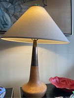 Full view of lamp on surface with shade illuminated, showing proportions and color