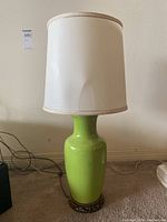 Front view of green ceramic lamp with white shade showing overall design and color