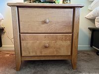 Front view of the wooden night stand showing two drawers with round wooden knobs and natural wood grain finish.