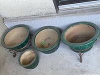 All four pots displayed together on concrete surface against stucco wall