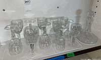 Twelve crystal glasses (some inverted) and crystal decanter displayed on shelf