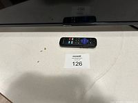 Flat screen TV laying face up with remote control on top, showing Hisense logo below screen.