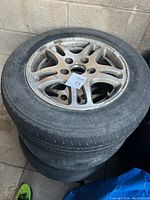 Four stacked tires fitted on aluminum alloy rims shown from top angle against a concrete wall.