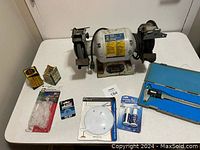 Bench grinder in center with various small tools and accessories on table around it