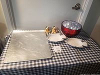 Photo showing aluminum cookie baking tray, two ceramic bear figurines, white fish plates, and red glass bowl on checkered tablecloth.