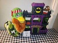 Photo of Batman Arkham Asylum plastic playset and camo stuffed duck toy with orange beard and red-white-blue headband on table