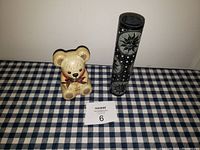 Bear shaped candy holder standing next to black candle holder on checkered tablecloth
