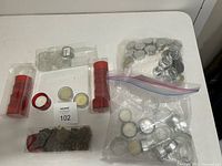 Overview photo including two packs of tea light candles, two red glass candle holders, two bags containing loose tea light candles, and some loose glass holders.