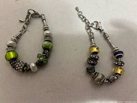 Two charm bracelets with mixed beads on a white background