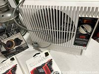 Photo shows a white RoadPro ThermSport portable electric heater with fan and temperature knob, a RoadPro Swivel Air Vent Clip in black and red, and a boxed Solid Grip Clip 2-pack in black.
