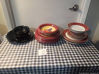 Photo of all plates grouped into three sets: black plates, red grapevine motif plates, and white plates with red and gold borders.