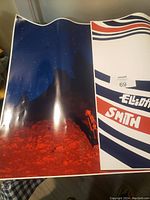Photo shows entire Elliott Smith poster with one side depicting dark rocky landscape under starry sky and the other side with graphic text design in red, white, and blue.