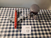 Photo showing both the red metal airplane model and the Star Trek Klingon Bird of Prey toy side by side on a checkered tablecloth.