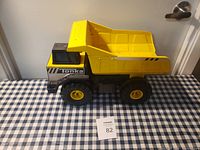 Side view of a large Tonka metal dump truck showing yellow dump bed and black and silver cab with Tonka logo.