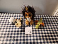 Photo showing four vintage TY stuffed animals: lion, seal, chameleon, and cow on checkered cloth.