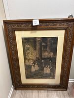 Full view of vintage picture in carved wooden frame leaning against a wall