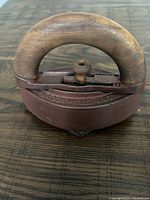 Top-down view of the antique cast iron iron showing the wooden handle and maker's mark embossed on metal.