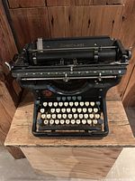 Front view of antique Underwood typewriter showing keyboard with missing 'W' key, cast iron base, and paper holder with Underwood branding.