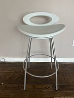 Front view of modern white plastic and metal bar stool on hardwood floor