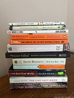 Books stacked horizontally showing titles and authors on spines.