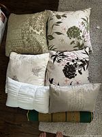 Top view showing six cushions including damask, floral, pleated white, and decorative stitched cushions.