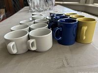 16 espresso cups of various colors arranged on table
