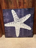 Front view of large square canvas print depicting a white starfish on dark blue textured background.