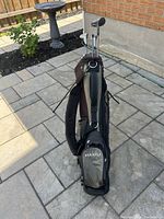 Partial right-handed golf club set in MaxFli standing golf bag seen outside on stone patio.