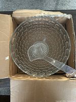 Top view of the clear glass punch bowl with textured oval bubble pattern and clear glass ladle inside, showing shape and condition of the bowl and ladle including the chip on bowl's rim.