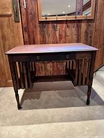 Front view of the vintage wood desk showing drawer, legs, and side slats