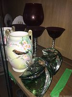 Lot displayed on cabinet shelf with candlestick holders, vase, and ruby stemware visible