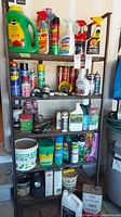 Full view of shelving unit filled with assorted partial and full bottles of chemicals including gardening feed, insecticides, lubricants, and cleaning sprays.