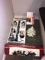 Overview of the lot on floor showing boxed tealight holder, ceramic tree, and string lights with character bulbs.