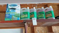 Four one-gallon jugs of Hydro Grass Spray Green liquid lawn fertilizers and product box on shelf.