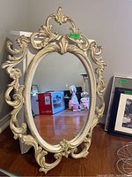 Full view of the ornate oval wall mirror showing detailed carving and size relative to nearby objects