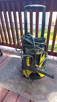 Front view of Karcher electric power washer with coiled hose and power cord on outdoor surface.