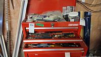 Red Craftsman toolbox with open drawers showing assorted hand tools including wrenches and screwdrivers