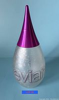 Pearlescent glass Evian water bottle with pointed metallic purple cap and year 2003 inscription.