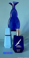 Three collector bottles including a tall cobalt blue glass decorative bottle, a Blue Stratos cologne bottle (50 ml), and an Eau de Beauty fragrance bottle